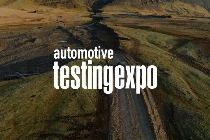 Text automotive testing expo appears in large white letters over a landscape featuring a winding dirt road, grassy terrain, and hills in the background, capturing the spirit of industry events.