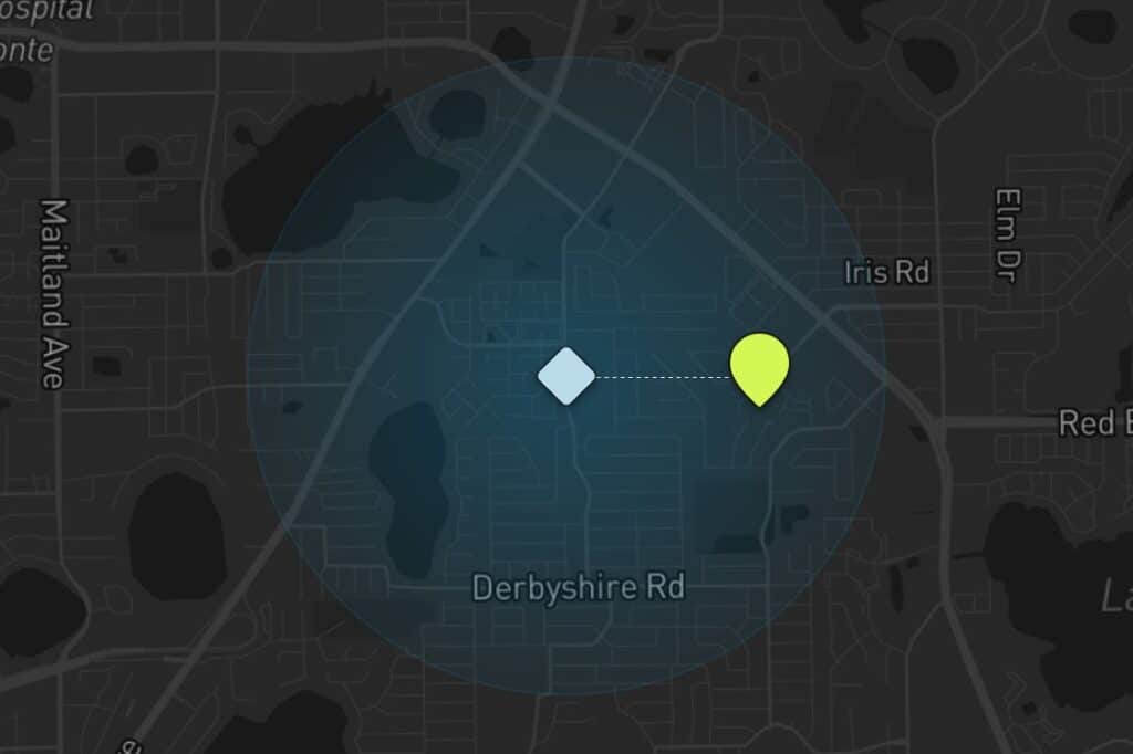 A dark map with a blue highlighted circular area, centered on a blue diamond symbol. A dotted line leads east to a yellow marker, located near Iris Rd and Derbyshire Rd. Nearby streets and bodies of water are visible.