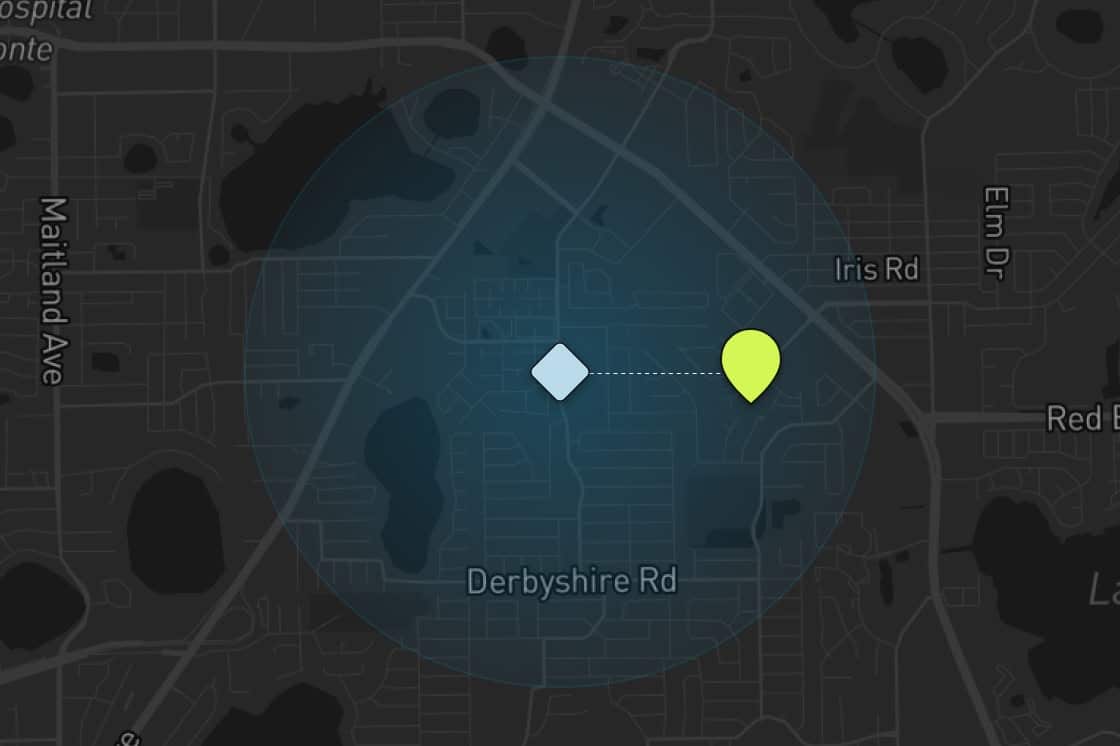 A dark map with a blue highlighted circular area, centered on a blue diamond symbol. A dotted line leads east to a yellow marker, located near Iris Rd and Derbyshire Rd. Nearby streets and bodies of water are visible.