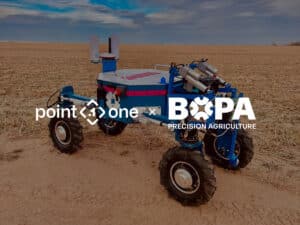 A blue, four-wheeled robotic vehicle is parked on a field under a cloudy sky, showcasing precision ag technology. Overlaid logos read point one and BOPA Precision Agriculture.