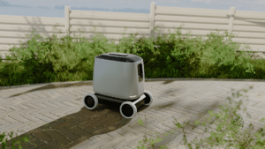 A small, autonomous delivery robot with four wheels navigates a paved path next to greenery and a white fence, using shared maps to understand its location context under the sunny sky.