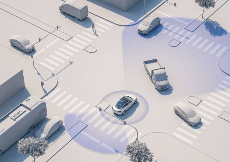 Aerial view of a city intersection with several vehicles and pedestrians; a car in the center displays blue sensor zones, illustrating autonomous or assisted driving technology detecting its surroundings.