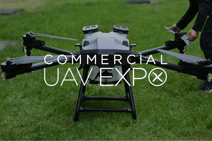 A large black UAV sits on grass, with a person adjusting it in the background. Overlaid text reads Commercial UAV Expo.